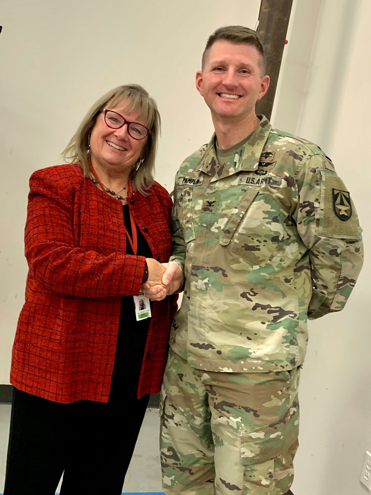 Director, COL Jeremy Pamplin, congratulates Dr. Loretta Schlachta-Fairchild on a long and successful career in support of Military Medicine and presents her with the Director’s Coin.
