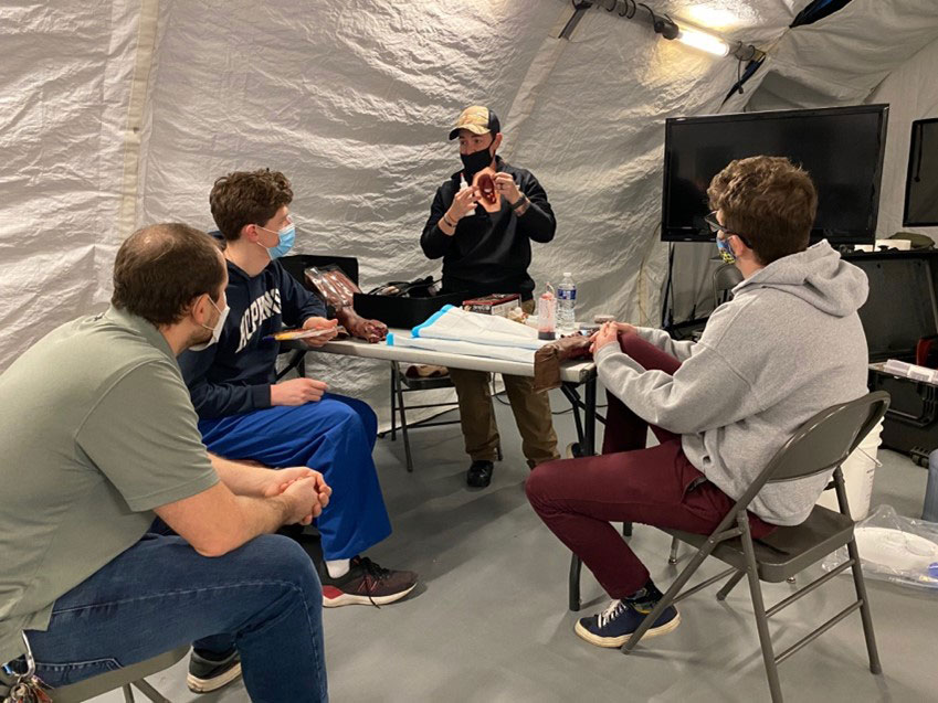Instructor from Strategic Ops teaches our sim staff how to repair, moulage, & set up casualty simulations utilizing cut suits for more realistic casualty care scenarios. From left to right: Mr. Oliver Allen, Mr. Zachary Buono, and Mr. James “Jimmy” Gaudaen get trained by the STOP instructor on the art of moulage.