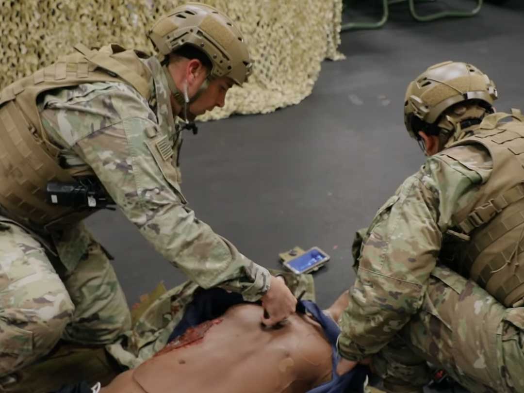 photos of 2 combat medic attending to manequine